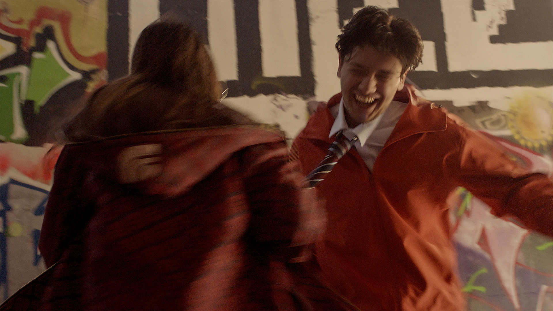 Courtney and Nathan laughing against a graffitied wall
