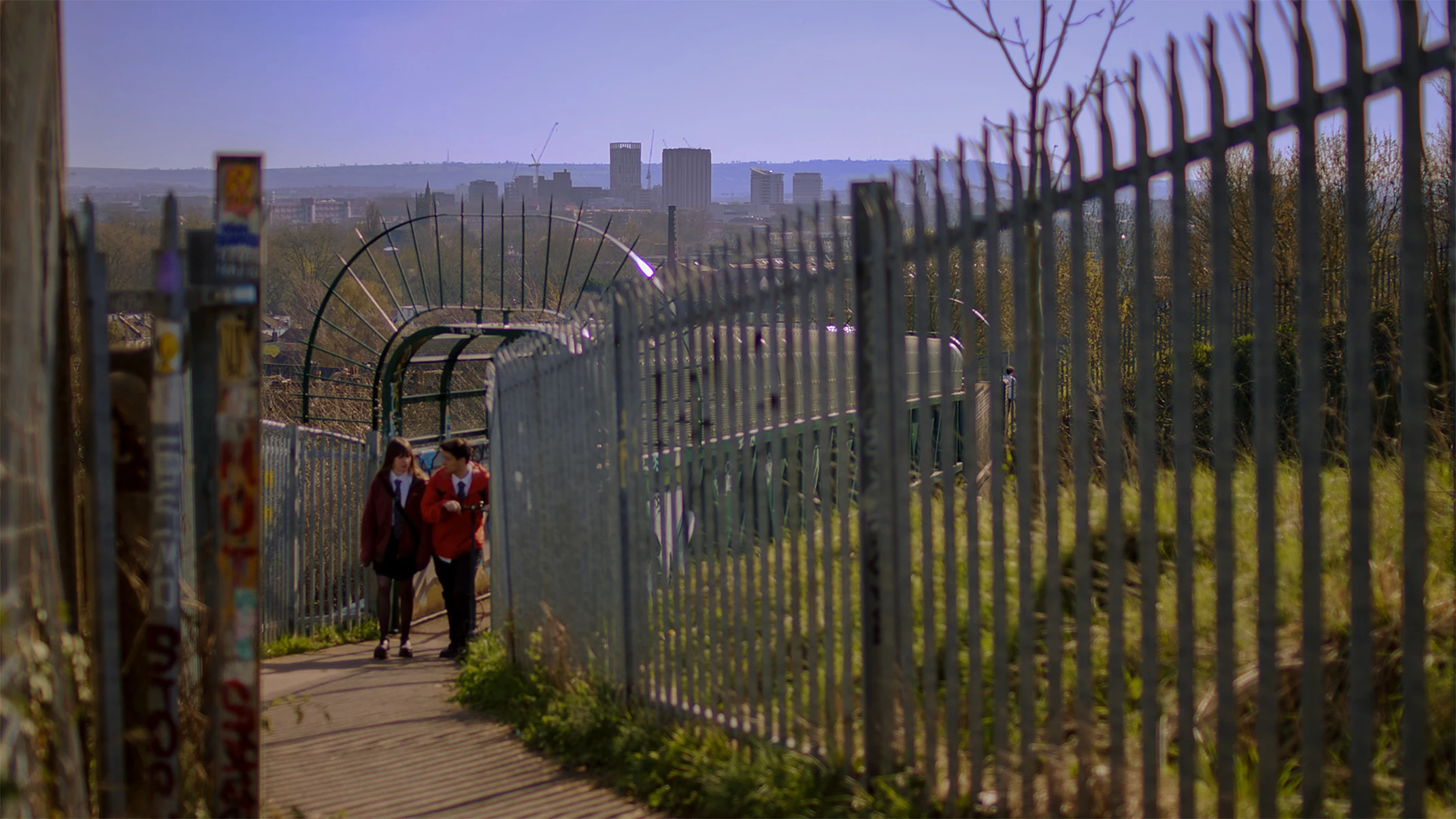Courtney and Nathan walking a fenced path above the Bristol skyline